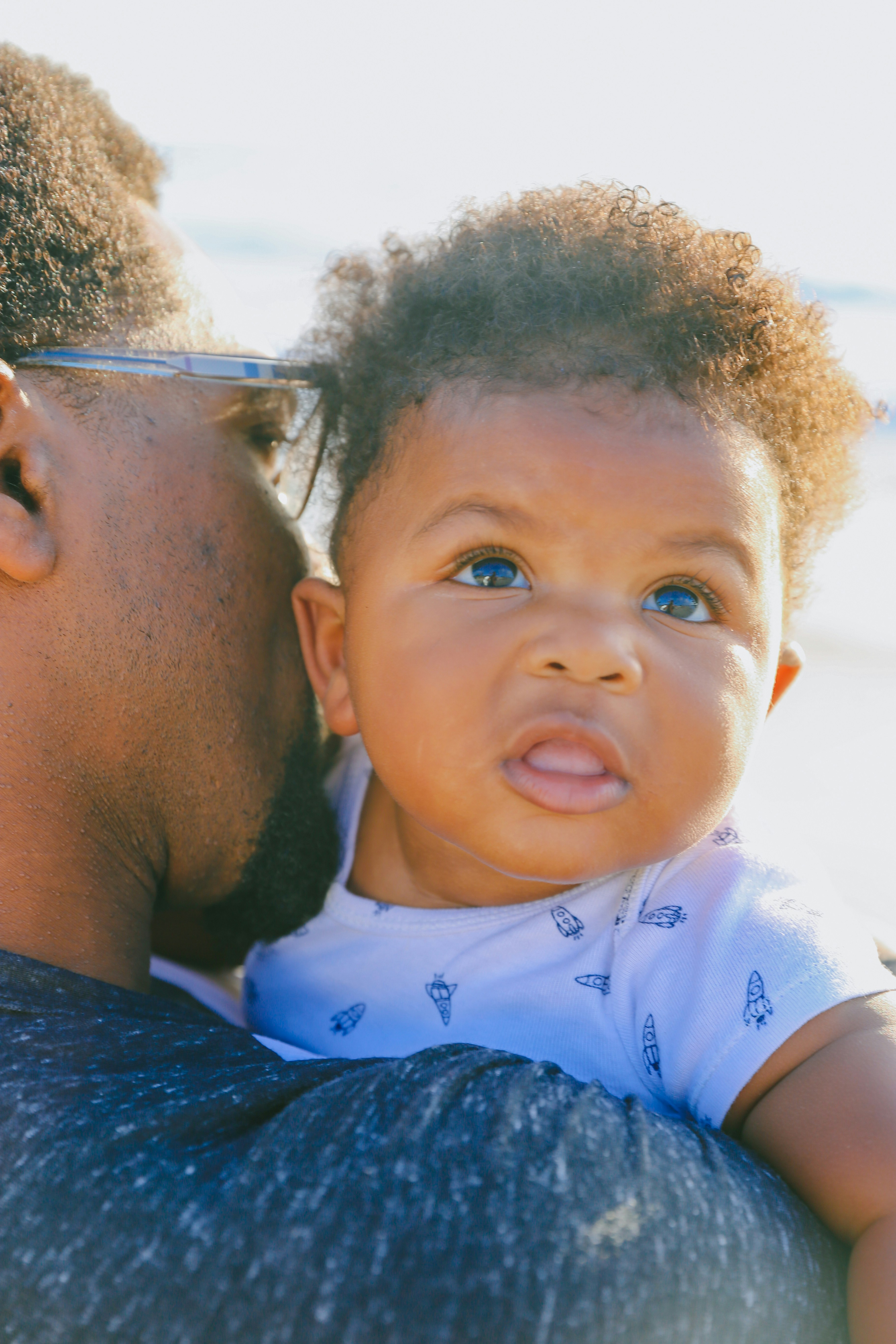 Candid seaside photo of a dad and son bonding, showing happiness, connection, and representation.